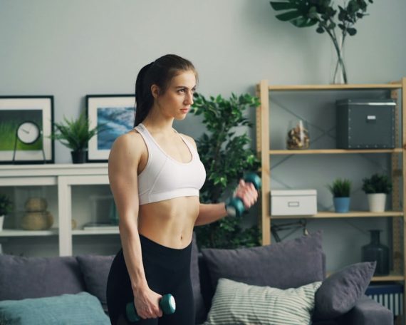a woman in a sports bra top is holding a dumb